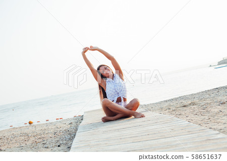 Beautiful woman with long hair doing yoga on the beach by the sea Beautiful woman with long hair doing yoga on the beach by the sea 58651637