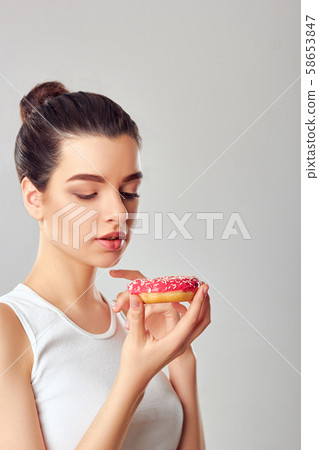 Close up portrait of a hungry girl eating donuts 58653847