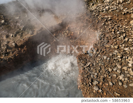 Steam over a boiling mud hole in Iceland 58653963