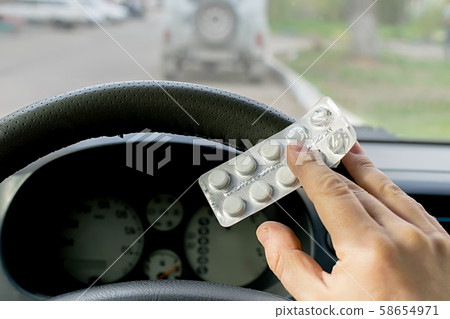 driver hand holds a package of pills 58654971