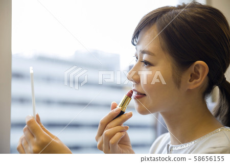 Young woman repairing makeup in store or office Young woman repairing makeup in store or office 58656155