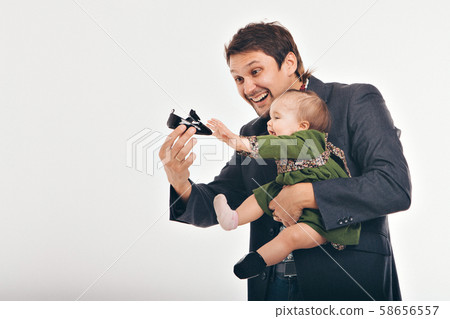dad shows the child a black Shoe.the kid reaches for the Shoe. family tries on clothes. the concept of clothing for the whole family, advertising shoes, Cinderella dad shows the child a black Shoe.the kid reaches for the Shoe. family tries on clothes. the concept of clothing for the whole family, advertising shoes, Cinderella 58656557