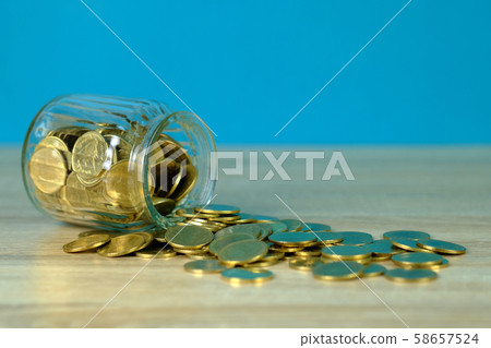 Coin money in the glass jar on table with green Coin money in the glass jar on table with green 58657524