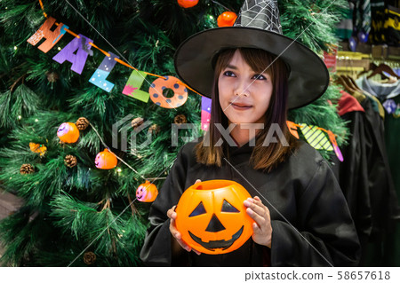 Beautiful young surprised woman or Halloween Witch dark style with holding a pumpkin and black drink in Halloween celebrate night party. Copy space background and soft or select focus 58657618