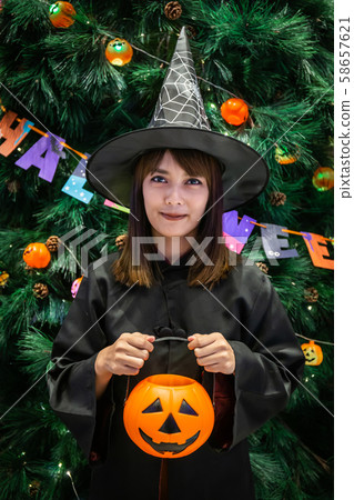 Beautiful young surprised woman or Halloween Witch dark style with holding a pumpkin and black drink in Halloween celebrate night party. Copy space background and soft or select focus 58657621