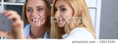 Two businesswomen in the office smile and do selfie 58657840