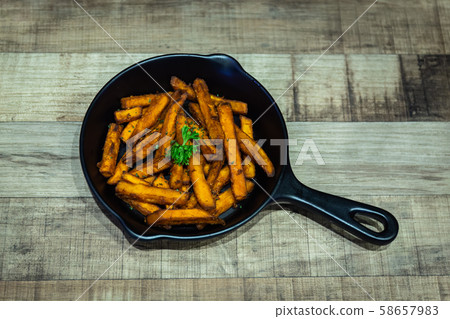 French fries in a black pan resting on a wooden table at a Halloween party French fries in a black pan resting on a wooden table at a Halloween party 58657983
