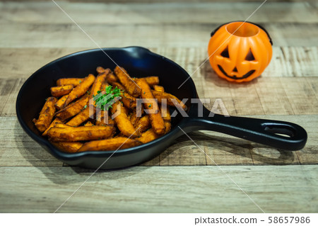 French fries in a black pan resting on a wooden table at a Halloween party French fries in a black pan resting on a wooden table at a Halloween party 58657986