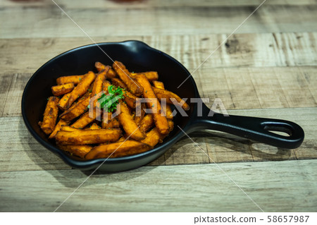French fries in a black pan resting on a wooden table at a Halloween party French fries in a black pan resting on a wooden table at a Halloween party 58657987