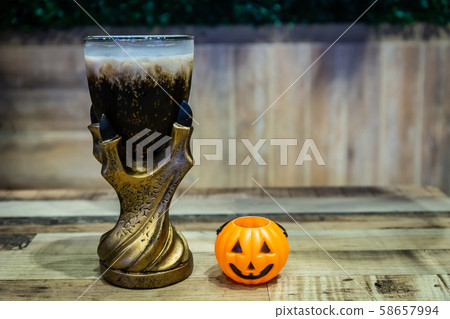 Black cola drink in a magic fantasy glass with a pumpkin, Halloween symbol on the table in Halloween night party 58657994