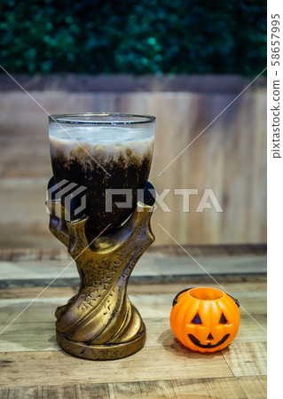 Black cola drink in a magic fantasy glass with a pumpkin, Halloween symbol on the table in Halloween night party 58657995