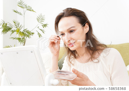 Young woman doing makeup at home Young woman doing makeup at home 58658368