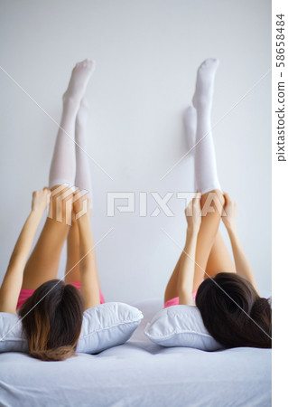 Close up of two sexy young women legs, lying on bed 58658484
