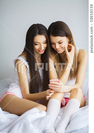 Two hot girls lying on a bed taking a photo of themselves 58658539
