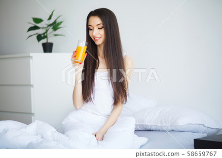 Casual smiling woman holding a glass of orange juice 58659767