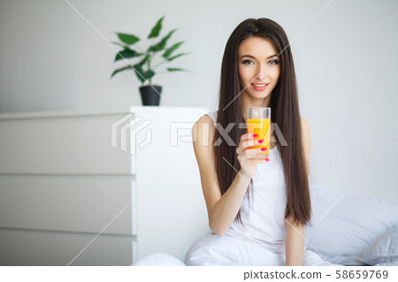 Casual smiling woman holding a glass of orange juice 58659769