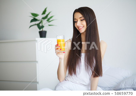 Casual smiling woman holding a glass of orange juice 58659770