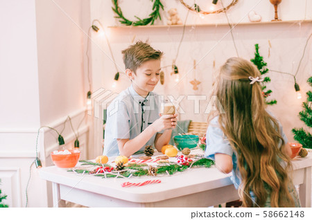 Cute little sister with long hair and an older brother drink cocoa in anticipation of Christmas. Christmas mood 58662148