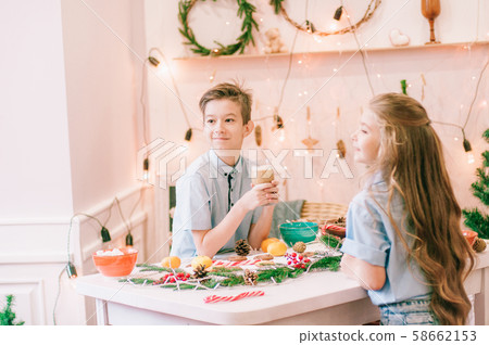 Cute little sister with long hair and an older brother drink cocoa in anticipation of Christmas. Christmas mood 58662153