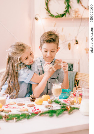 Cute little sister with long hair and an older brother drink cocoa in anticipation of Christmas. Christmas mood 58662160