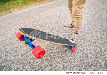 Close-up of male legs in rag sneakers on a longboard on the background of asphalt at sunset. Big Close-up of male legs in rag sneakers on a longboard on the background of asphalt at sunset. Big 58664396