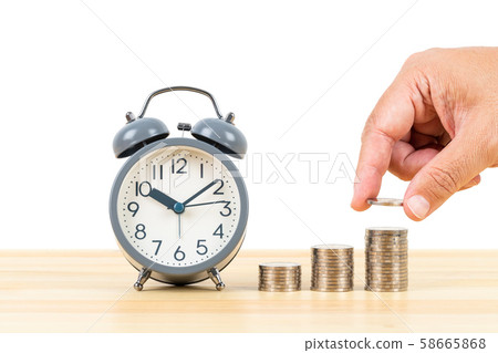 Coin stack and alarm clock on wooden desk with Coin stack and alarm clock on wooden desk with 58665868