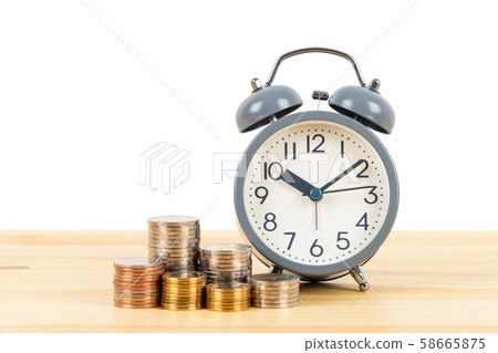 Coin stack and alarm clock on wooden desk  on 58665875
