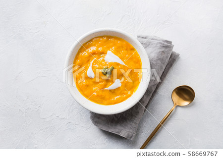 Pumpkin soup with cream on grey stone background. Pumpkin soup with cream on grey stone background. 58669767