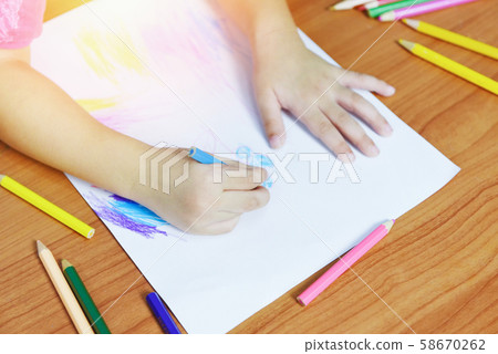 Girl painting on paper sheet with colour pencils 58670262