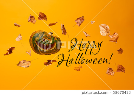 Scary pumpkin, flying dry leaves and inscription Happy Halloween 58670453