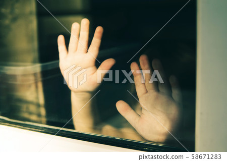Child standing with outstretched hands behind glass. Child standing with outstretched hands behind glass. 58671283