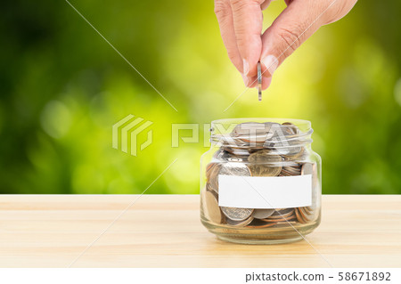 Coin glass jar container on wooden desk, on green Coin glass jar container on wooden desk, on green 58671892