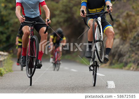 Cyclists riding on the rear wheel at the race. Balancing while driving on a road bike. Risky ride on one wheel Cyclists riding on the rear wheel at the race. Balancing while driving on a road bike. Risky ride on one wheel 58672585