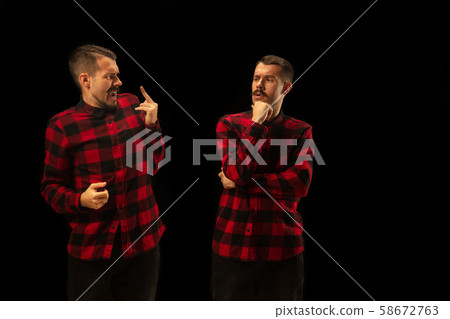 Young handsome man arguing with himself on black studio background. 58672763