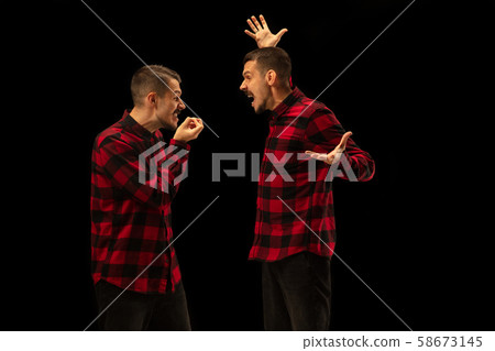 Young handsome man arguing with himself on black studio background. Young handsome man arguing with himself on black studio background. 58673145