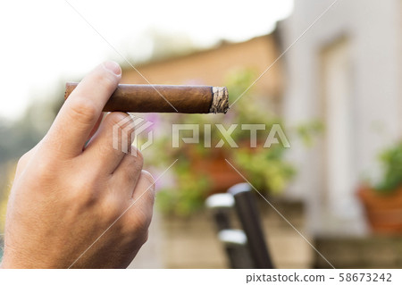 Detail of the hand of a smoking man holding a 58673242