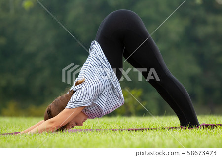 Young beautiful woman doing yoga exercise in green park. Healthy lifestyle and fitness concept. Young beautiful woman doing yoga exercise in green park. Healthy lifestyle and fitness concept. 58673473