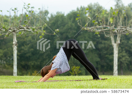 Young beautiful woman doing yoga exercise in green park. Healthy lifestyle and fitness concept. Young beautiful woman doing yoga exercise in green park. Healthy lifestyle and fitness concept. 58673474