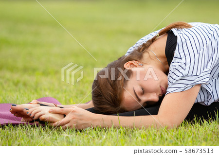 Young beautiful woman doing yoga exercise in green park. Healthy lifestyle and fitness concept. Young beautiful woman doing yoga exercise in green park. Healthy lifestyle and fitness concept. 58673513