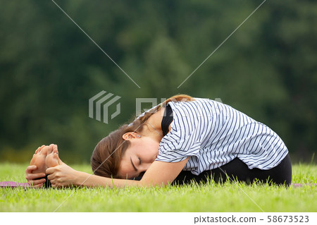 Young beautiful woman doing yoga exercise in green park. Healthy lifestyle and fitness concept. 58673523