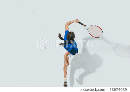 Young woman in blue shirt playing tennis. Youth, flexibility, power and energy. 58674089