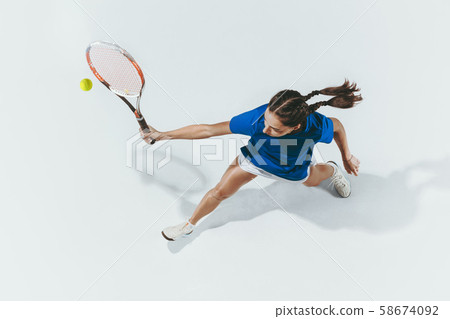 Young woman in blue shirt playing tennis. Youth, flexibility, power and energy. 58674092
