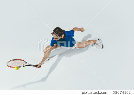 Young woman in blue shirt playing tennis. Youth, flexibility, power and energy. 58674102