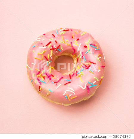 Pink donut decorated with sprinkles on coral background. Flat lay 58674373