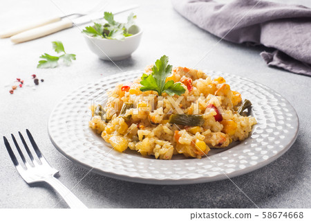 Pilaf with vegetables and chicken in a gray plate on a light background. 58674668