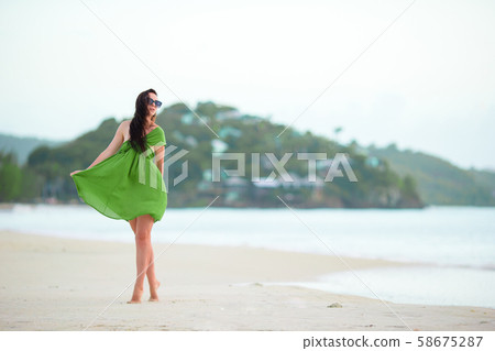 Young fashion woman in green dress on the beach 58675287