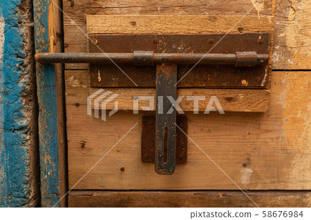 An old rusty latch of a rough wooden door An old rusty latch of a rough wooden door 58676984