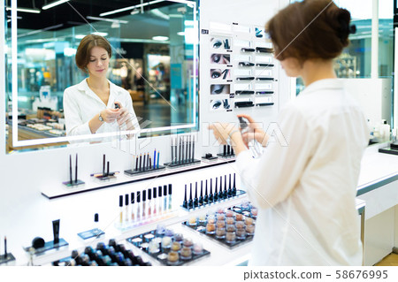 Young caucasian female testing spray at make up corner Young caucasian female testing spray at make up corner 58676995