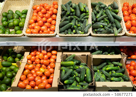 Supermarket shopboard with wicker baskets and carton boxes with tomatoes, cucumbers and avocado 58677271