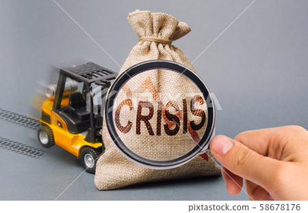 A magnifying glass looks at a yellow forklift truck can not lift the bag with the inscription crisis. Economic crisis, stagnation and recession of the economy. decline in production, purchasing power. A magnifying glass looks at a yellow forklift truck can not lift the bag with the inscription crisis. Economic crisis, stagnation and recession of the economy. decline in production, purchasing power. 58678176